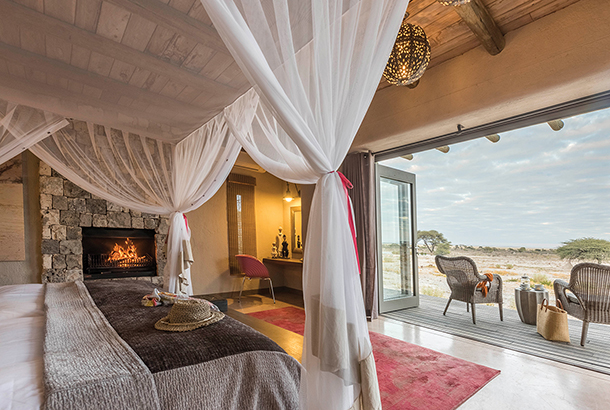 Bedroom with canopy bed, fireplace and open patio